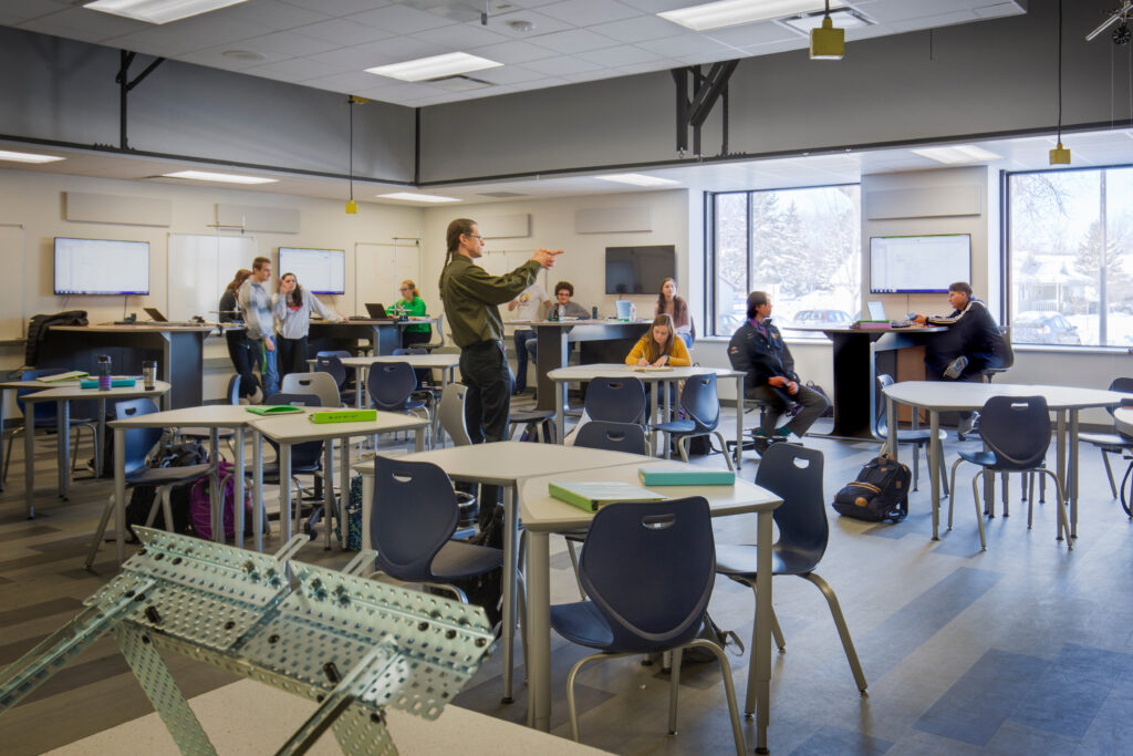 Students use a variety of lab and classroom furniture as an instructor speaks in a STEM room at DeForest Area High School
