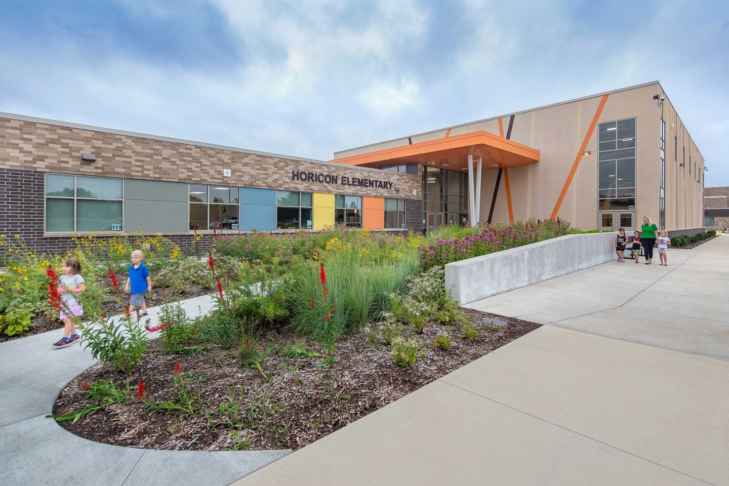 Colorful exterior of elementary school wing with plants and children walking