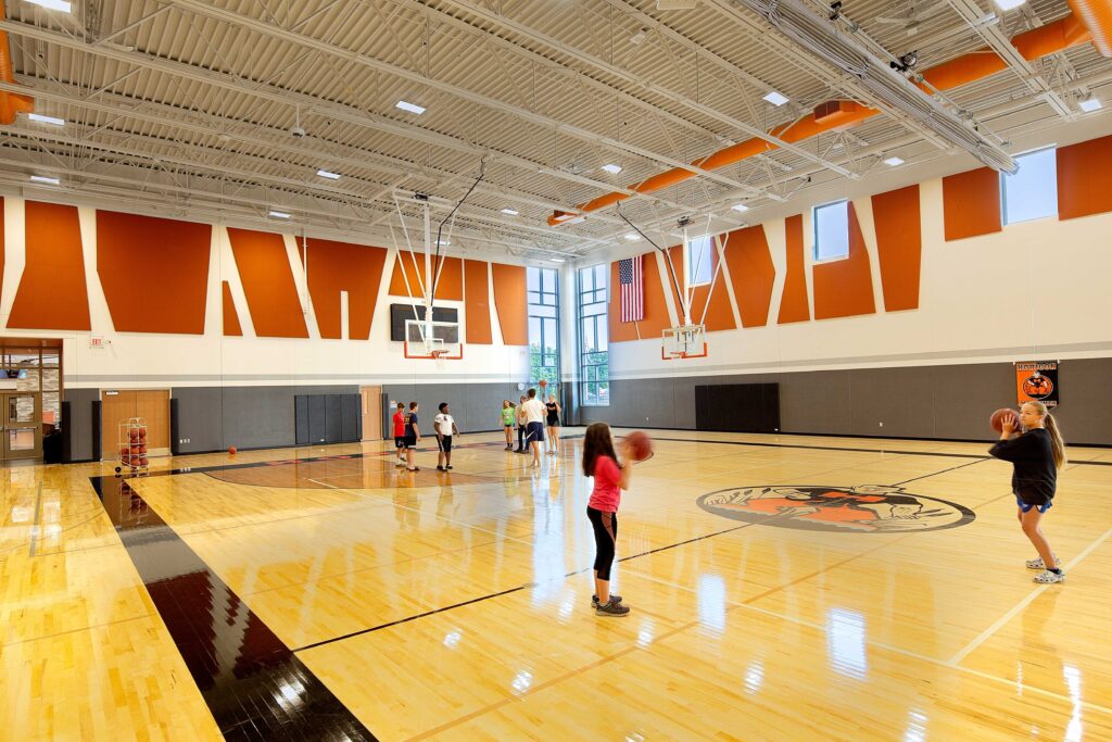 Students play in a large gymnasium with colorful panels