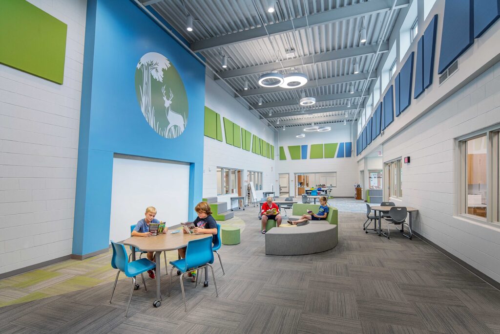 Students work at tables and large chairs in an open and colorful resource area