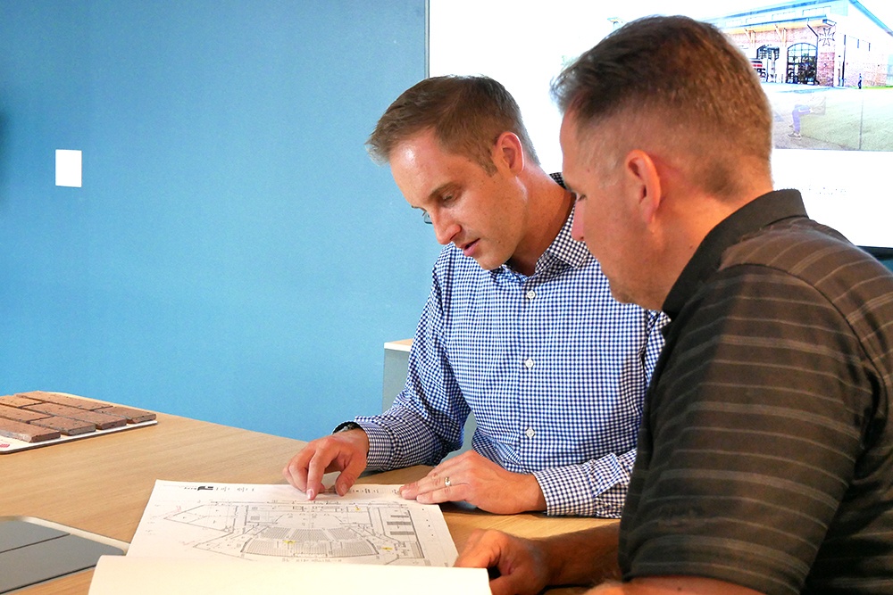 Bray team members are seated as they review architectural plans on a table