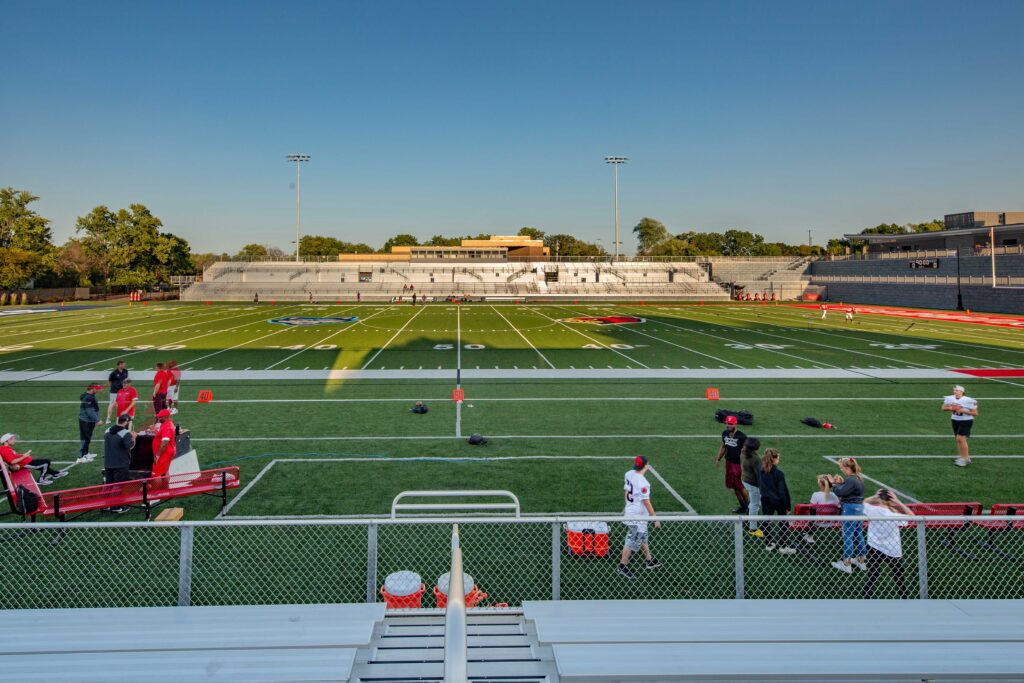 View of students using a football field from the bleachers at the 50 yard line