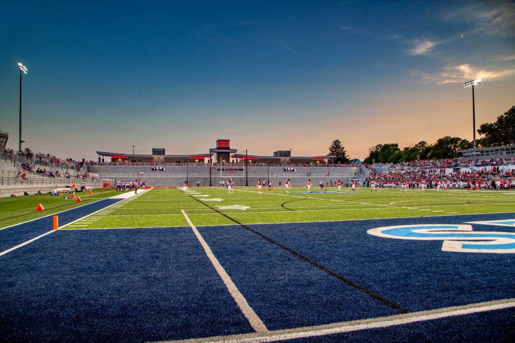 Wide view of football field and stadium from the end zone at dusk
