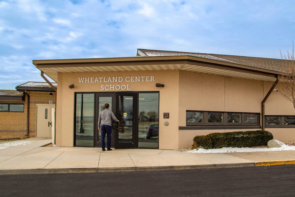 A person approaches the renovated entrance in an exterior view of Wheatland Center School