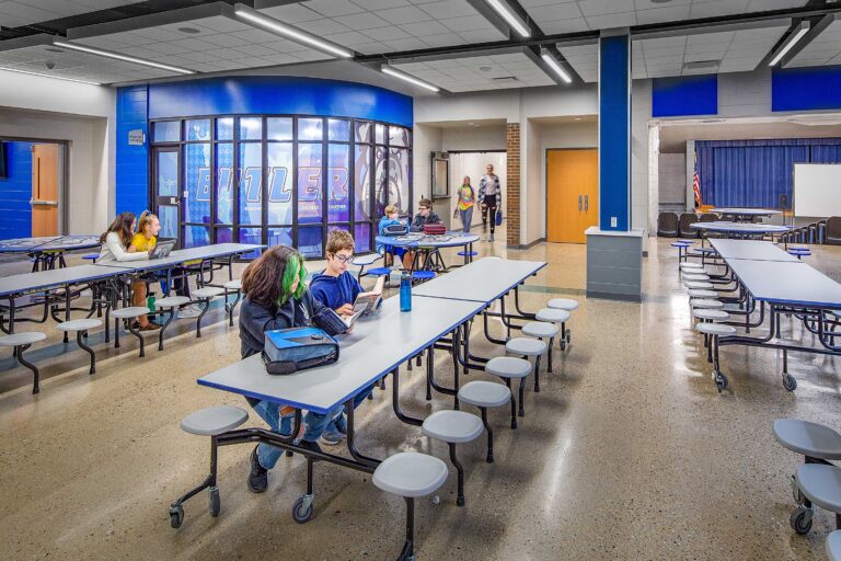 A curved glass wall shows the school name and mascot in a renovated commons area at Butler Middle School in Waukesha