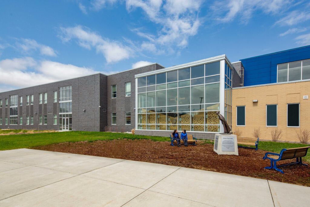 exterior photo of the chapel and academic wing with chapel glass windows and statue