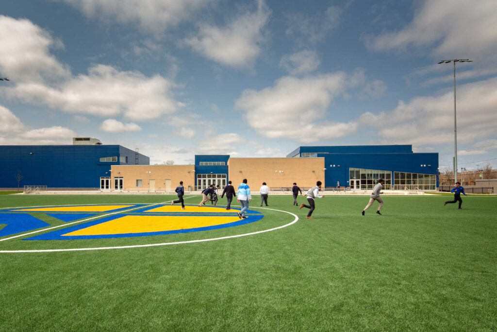 Turf field featuring Cristo Rey logo and exterior building in background.