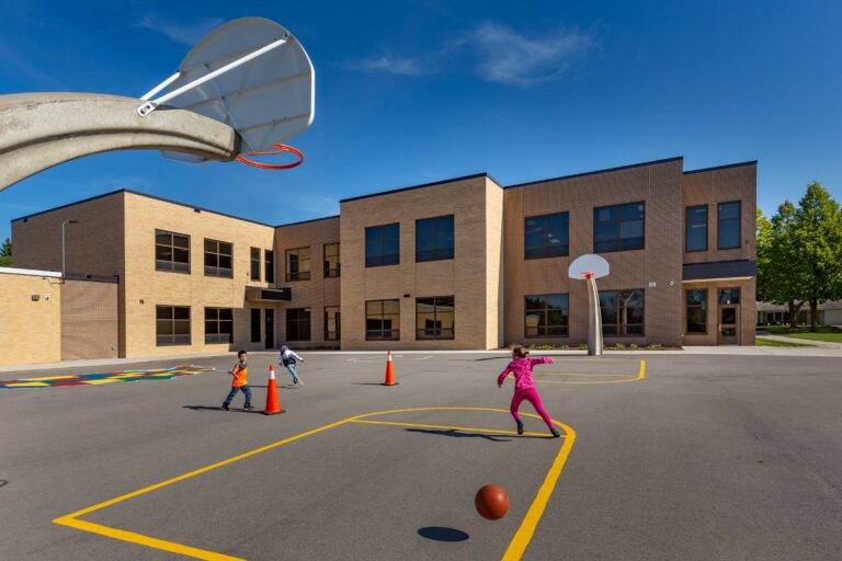 Basketball goals and colorful paint mark off an outdoor court as young children play at Eisenhower Elementary School in Green Bay