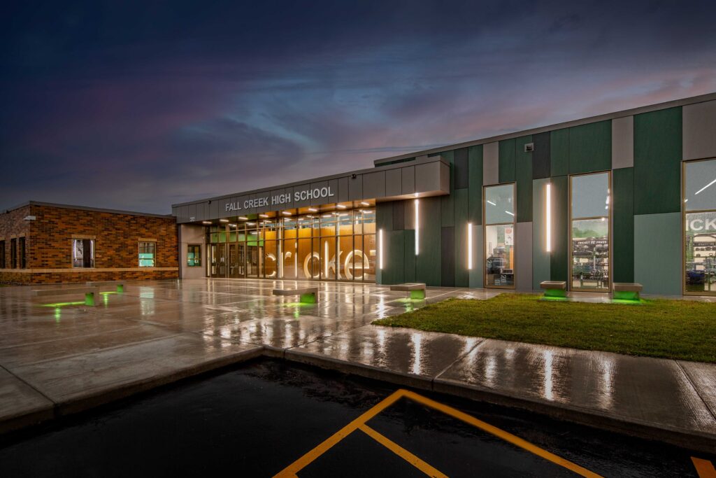 A night view into an entrance at Fall Creek High School showcases the school mascot name illuminated inside