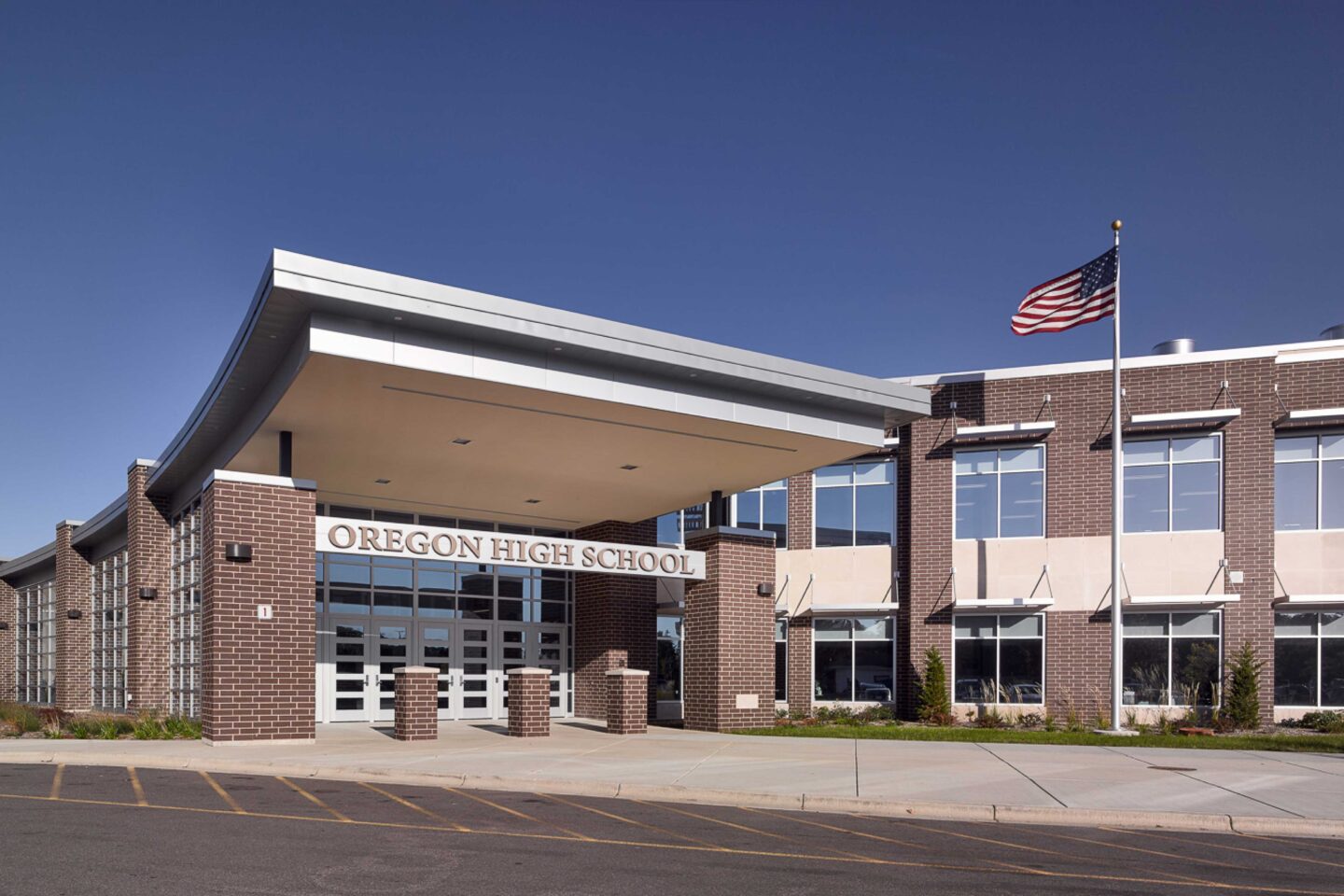 An exterior photo of the school's main entrance with a large canopy and flagpole nearby