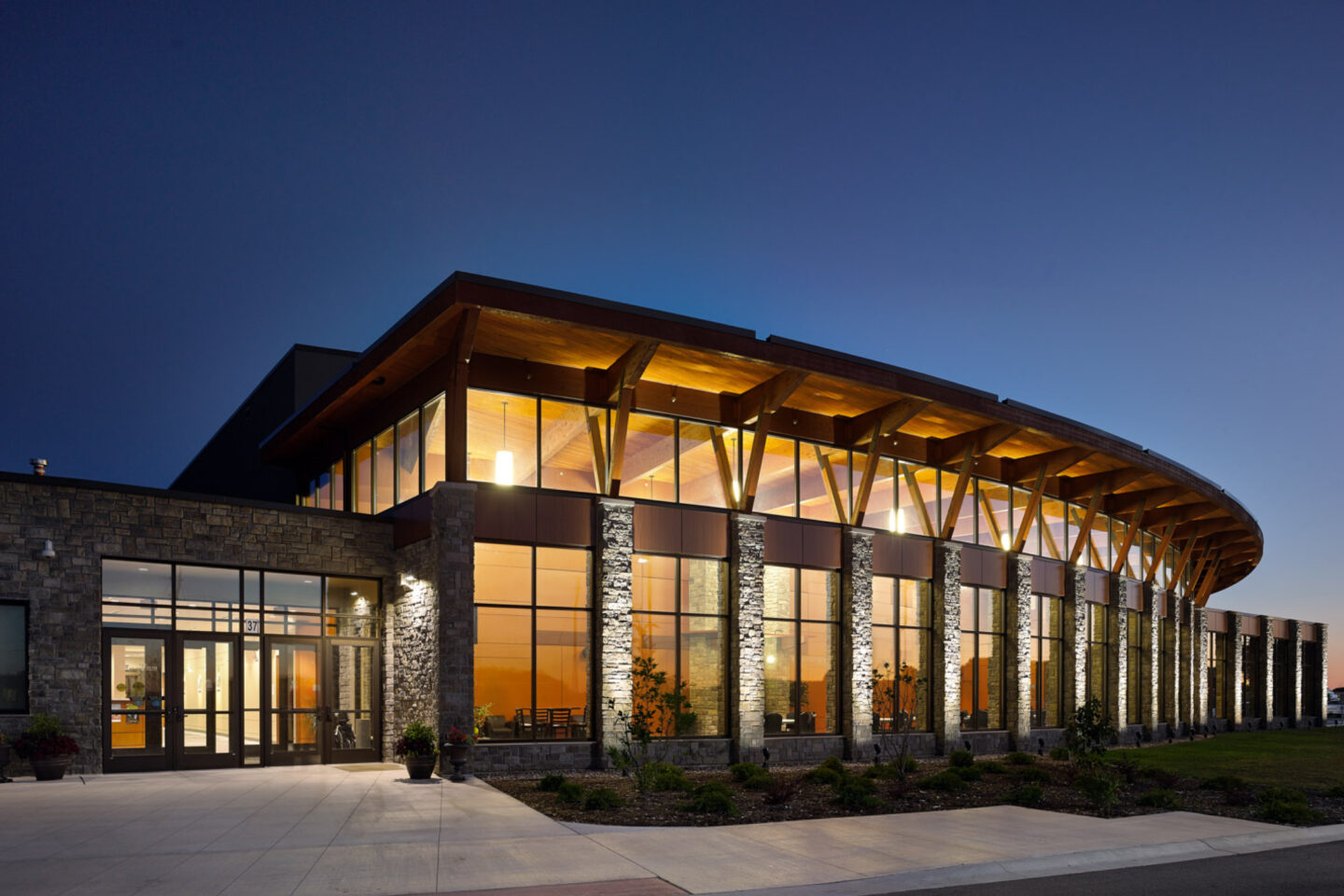 View of the exterior of a warmly lit, windowed performance building at night