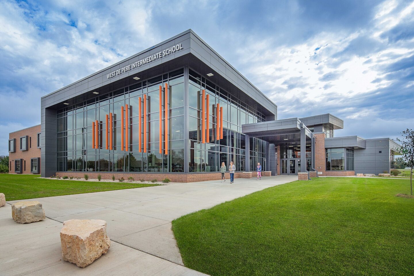 An exterior photo of the school featuring large windows and decorative orange fins