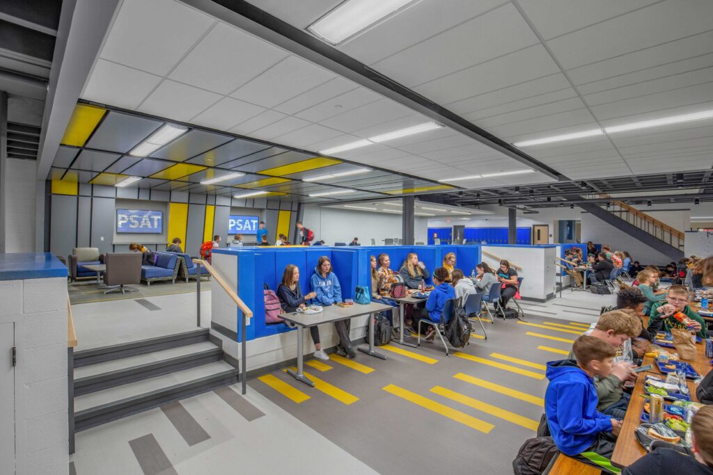 Students gather around multiple table and booth options in an open, split-level commons at Mukwonago High School