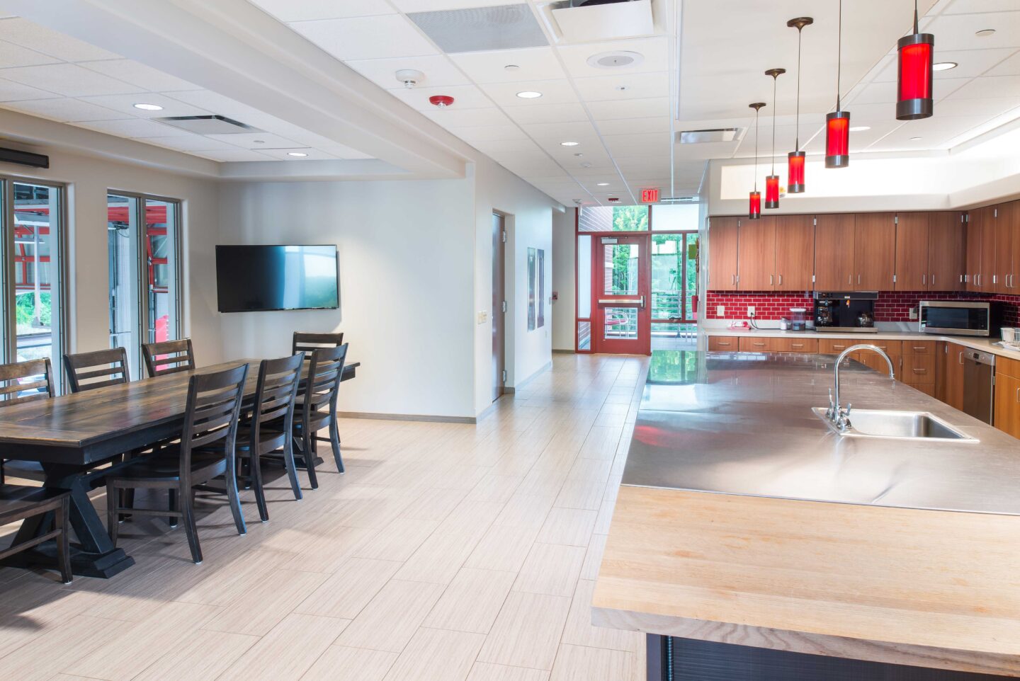 Natural light fills a red-accented kitchen connects to a large dining table at the Oak Creek Fire Station No. 1