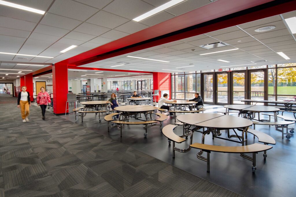Red ceiling and pillar accents set off an open cafeteria seating area from the hallway at Asa Clark Middle School