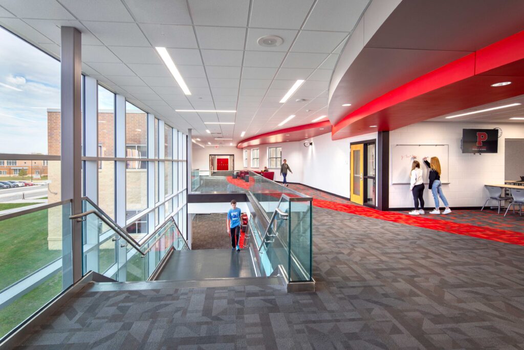 Windows flood light into a glassed-in staircase, with bright red accents in the landing area at Asa Clark Middle School