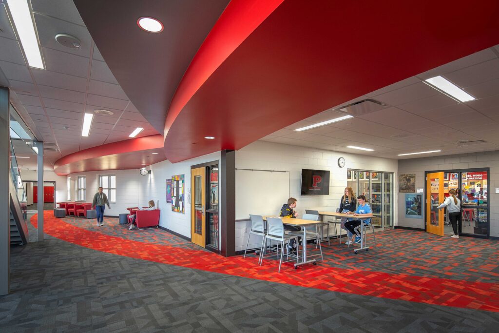 Colorful carpet and ceiling accents set off open resource areas off a wide hall at Asa Clark Middle School