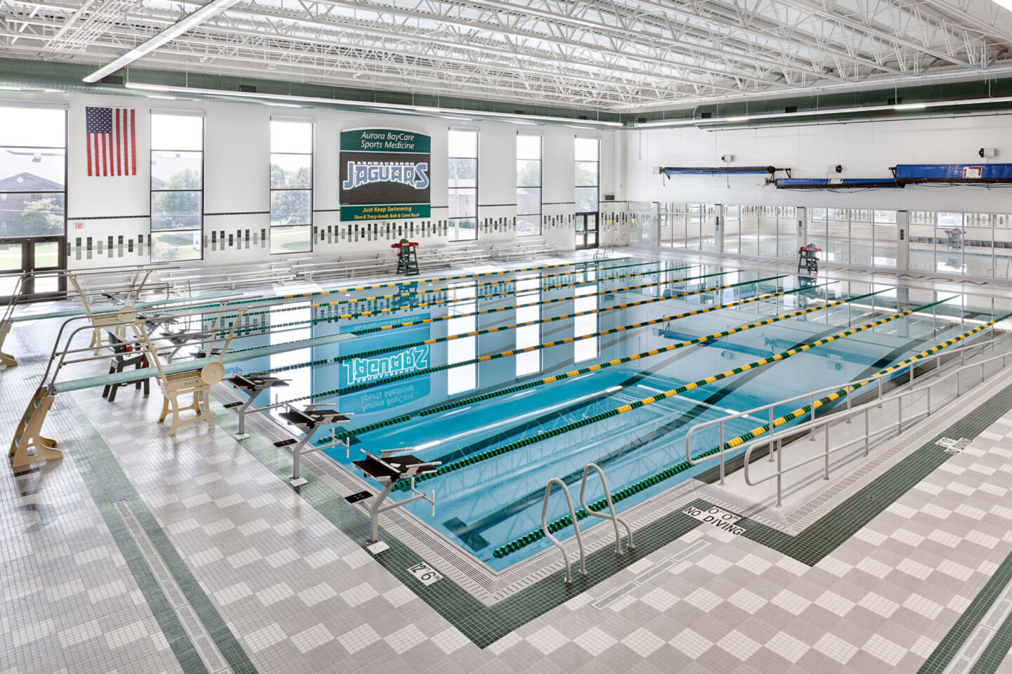 A view from the corner of a large pool with ample windows and light tiles