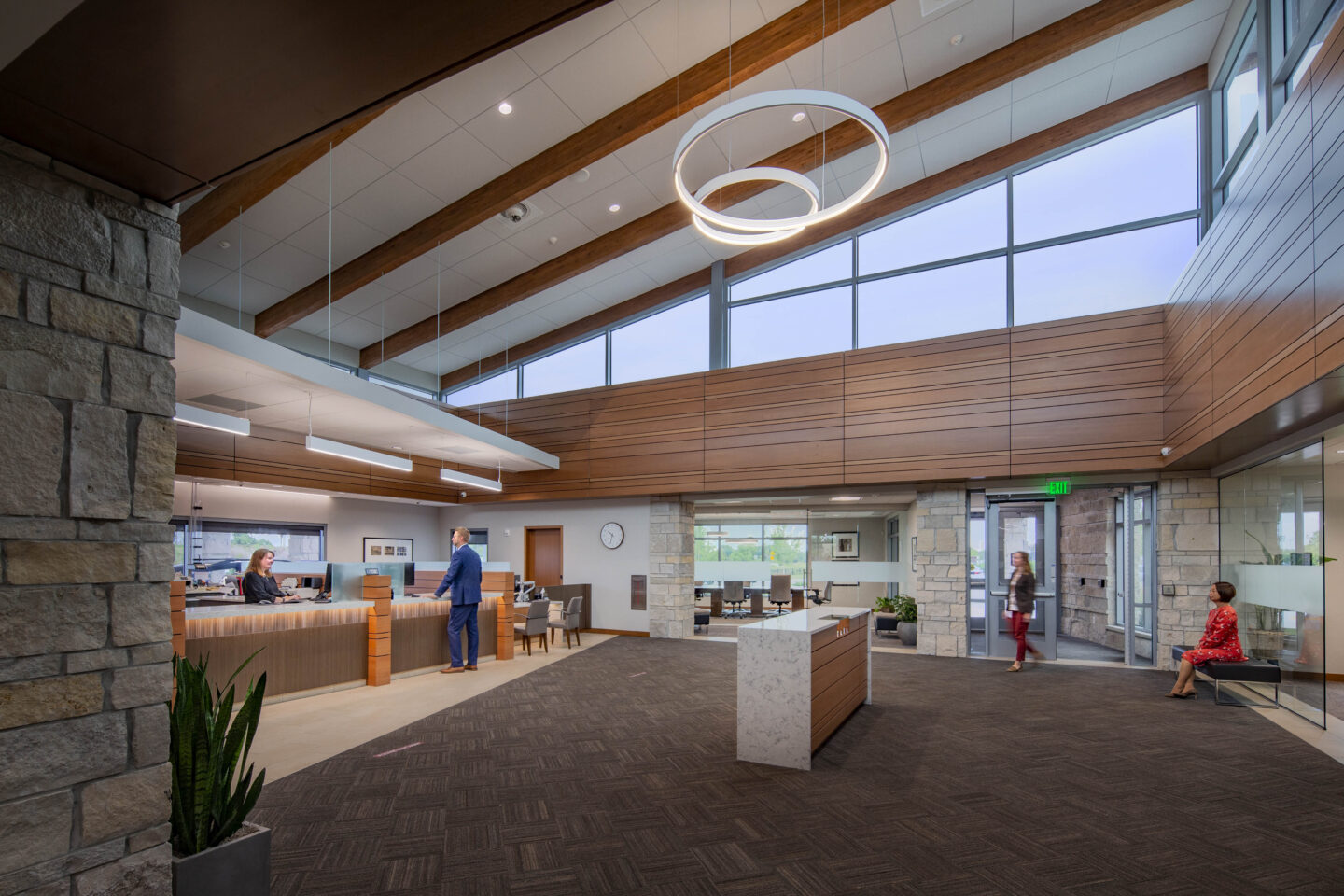 Modern, circular light fixtures illuminate an open, windowed bank lobby