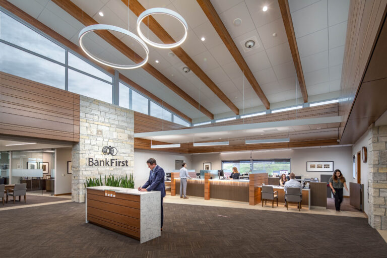 Modern, circular light fixtures illuminate an open, windowed bank lobby