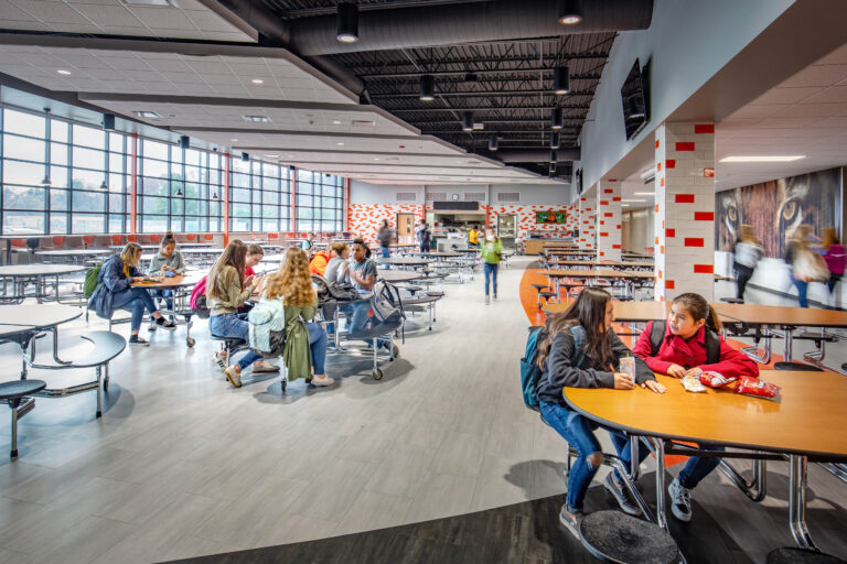 Students in the cafeteria, which features large windows and colorful wall tiles