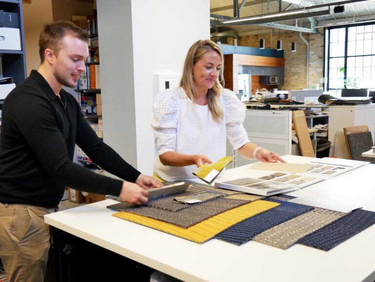 Two employees standing around a table looking at various fabric samples