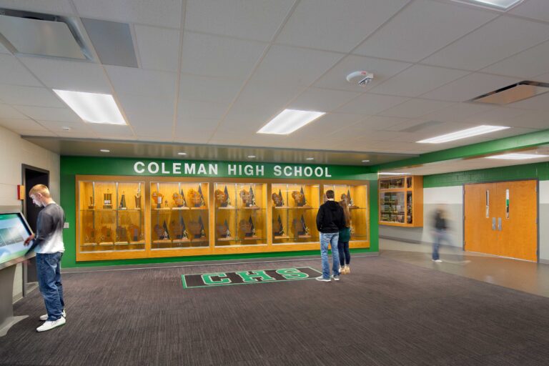 A school-branded entrance at Coleman High School includes a large display case full of awards.
