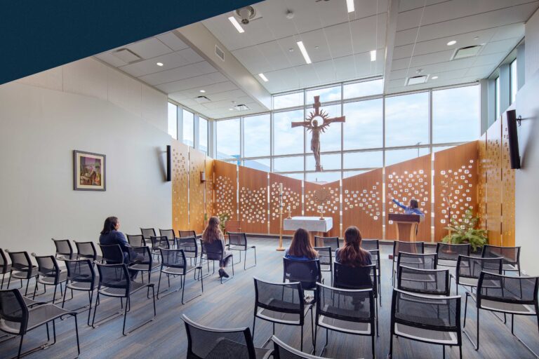 Inside of chapel looking South with wood paneling against window and cross centered.