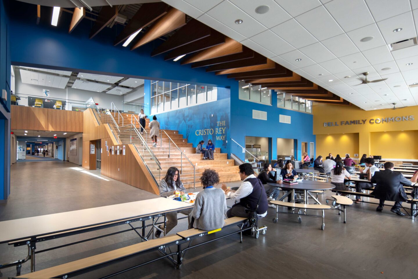 Commons/cafeteria area with view of stairs and ceiling wood paneling.