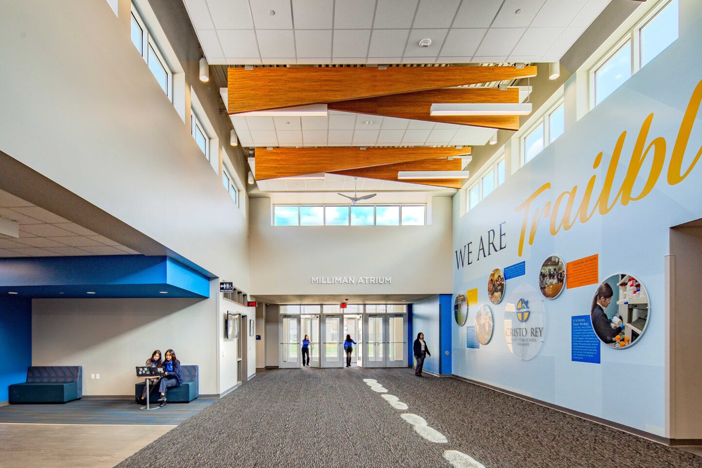 Lobby of the main entrance, featuring wood paneling on ceilings, high windows and branded wall.