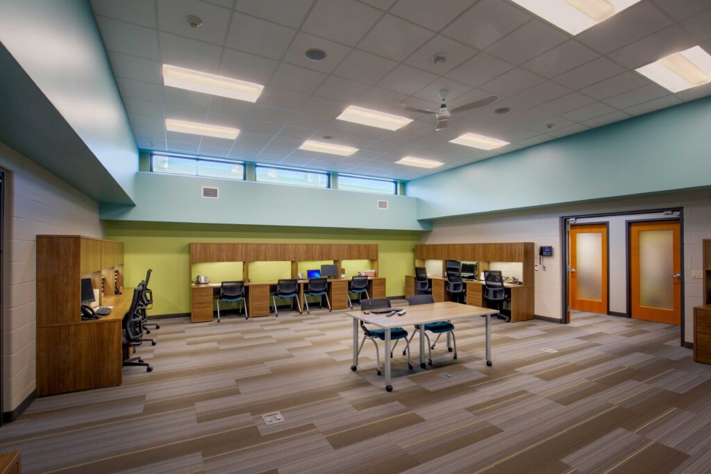 An open room with workstations and a strip of windows above allows for natural light and privacy in the public safety building