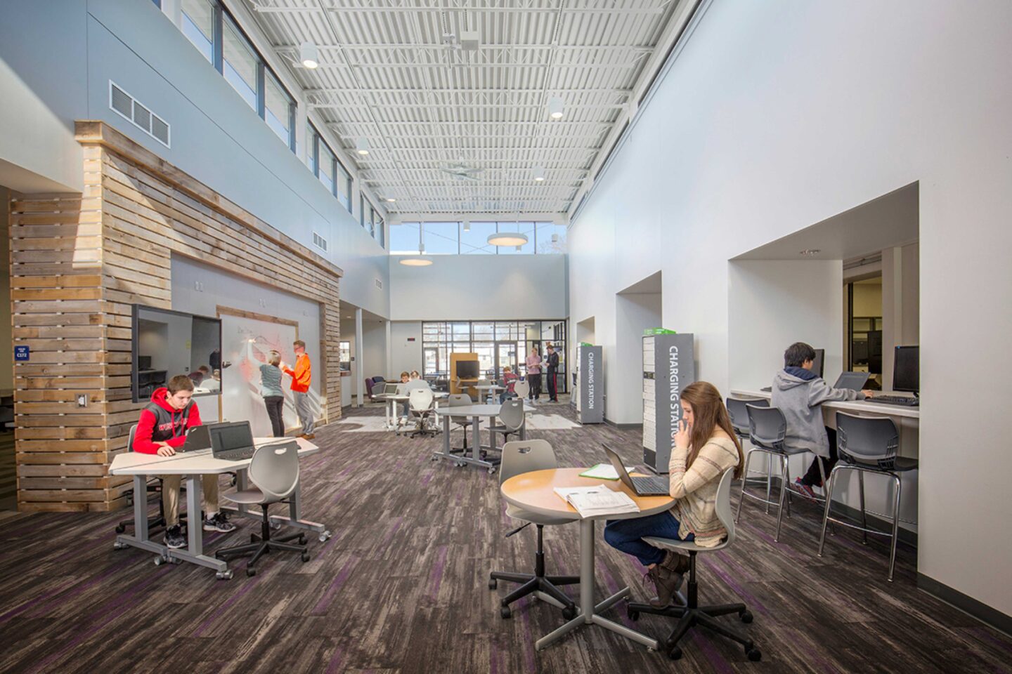 An open space in the DeForest Area High School STEM section features low tables, high counters, monitors, and whiteboards for collaborative work