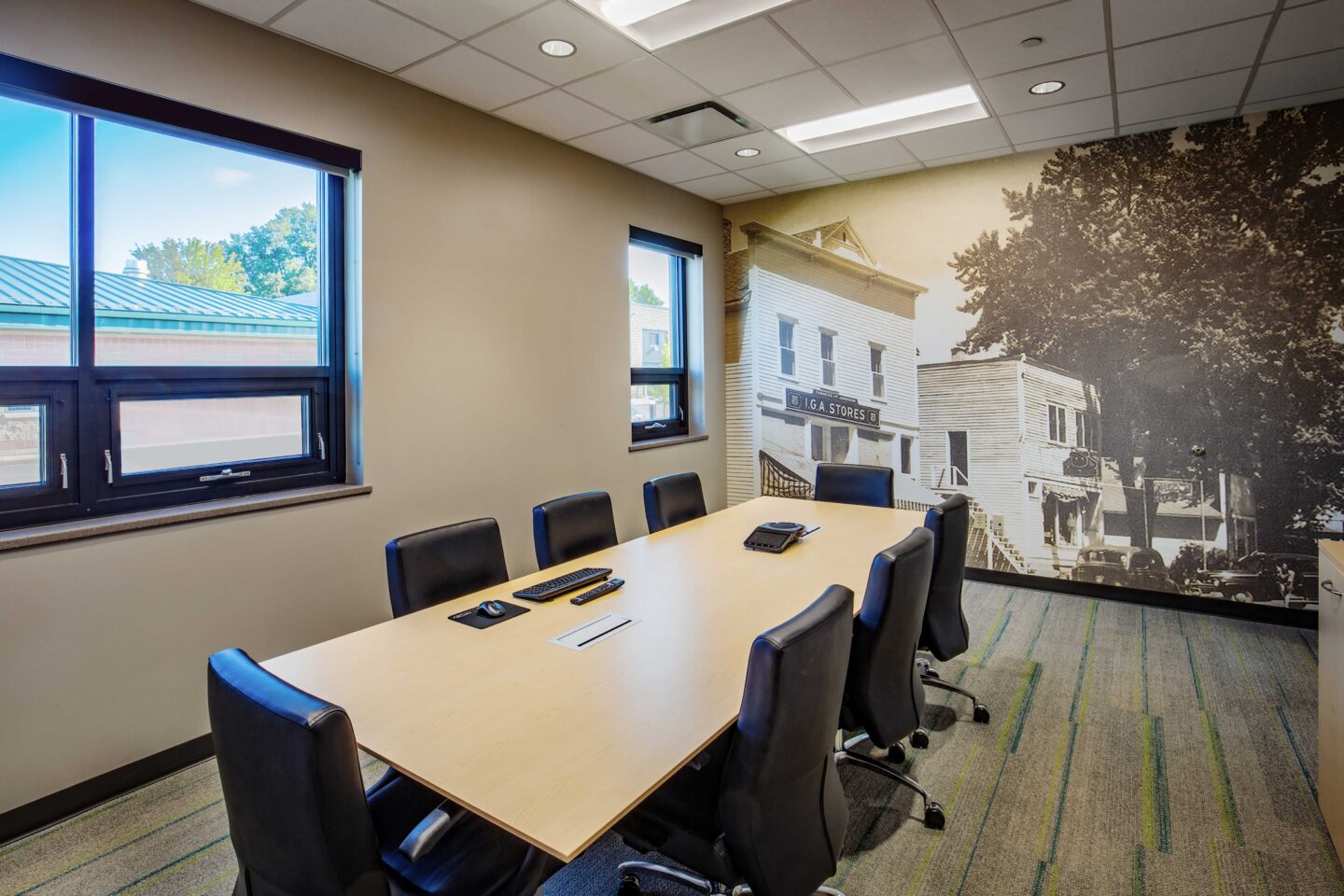 A small conference room with multiple windows features a historic photo mural of the Village of DeForest