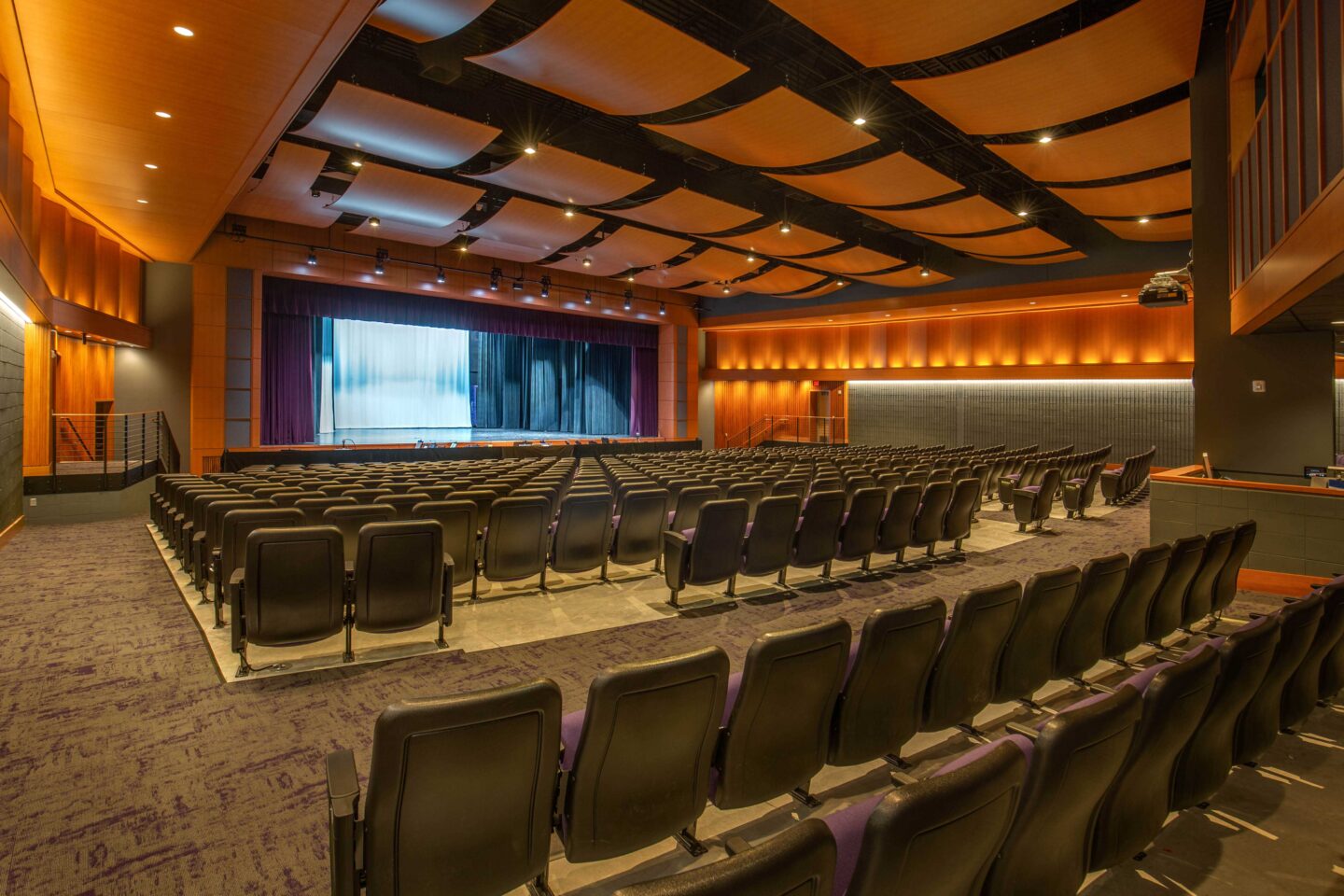 A view of the renovated auditorium featuring a large stage, new seating, and acoustic wall and ceiling panels