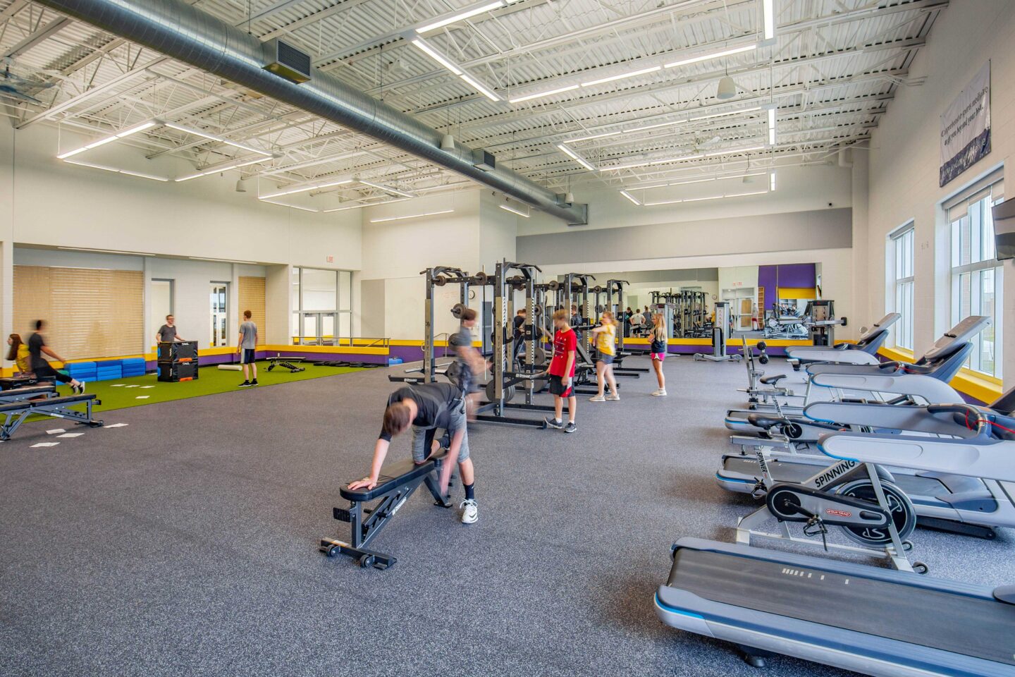 Students utilize the equipment in the new fitness center, which includes tall ceilings and large windows to create a bright and spacious environment