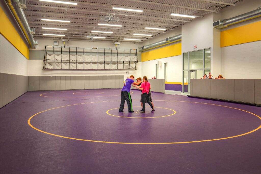 Students practice drills in the wrestling room with two full-sized wrestling courts