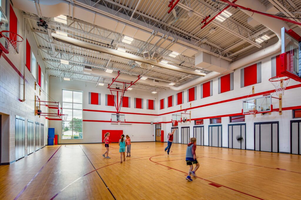 Students play in a bright gym space accented with red at Eleva-Strum Elementary School