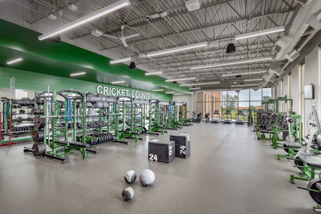 A large, well-stocked weight room features large windows and school colors at Fall Creek High School