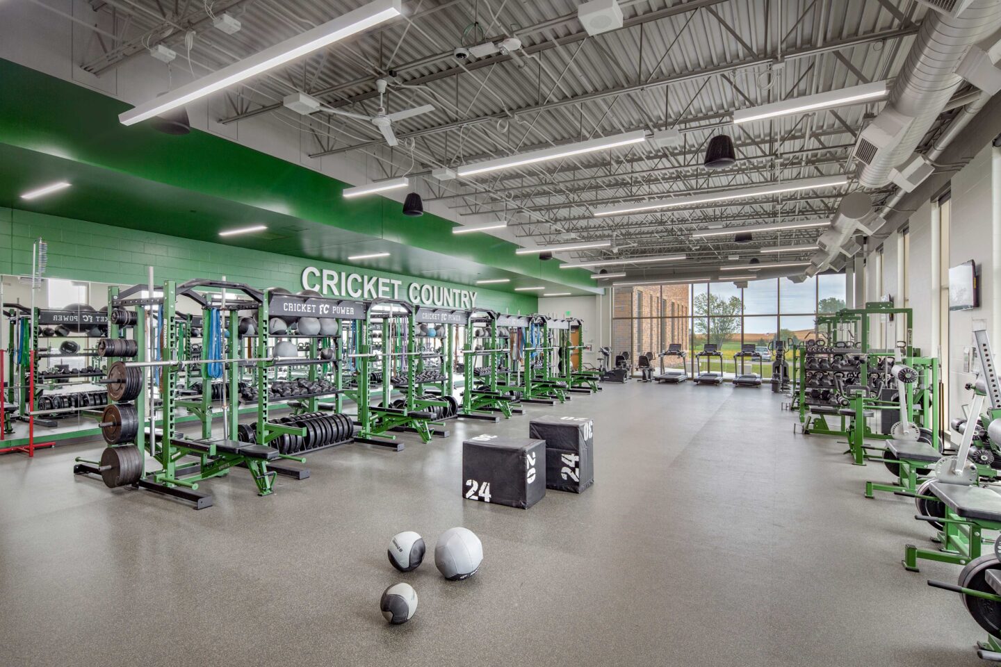 A large, well-stocked weight room features large windows and school colors at Fall Creek High School