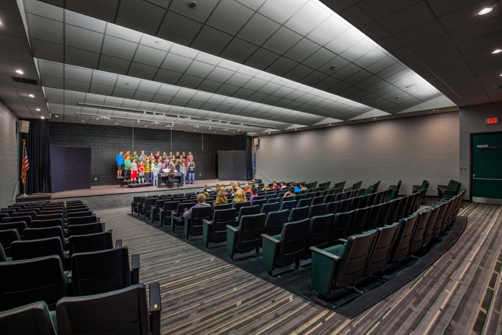Students perform on stage in an intimate, modern theater space at Florence Middle + High School