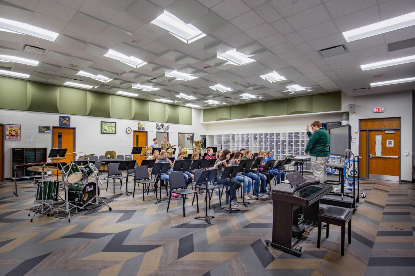 A conductor leads a student band in an acoustic-paneled, open band room at Florence Middle + High School