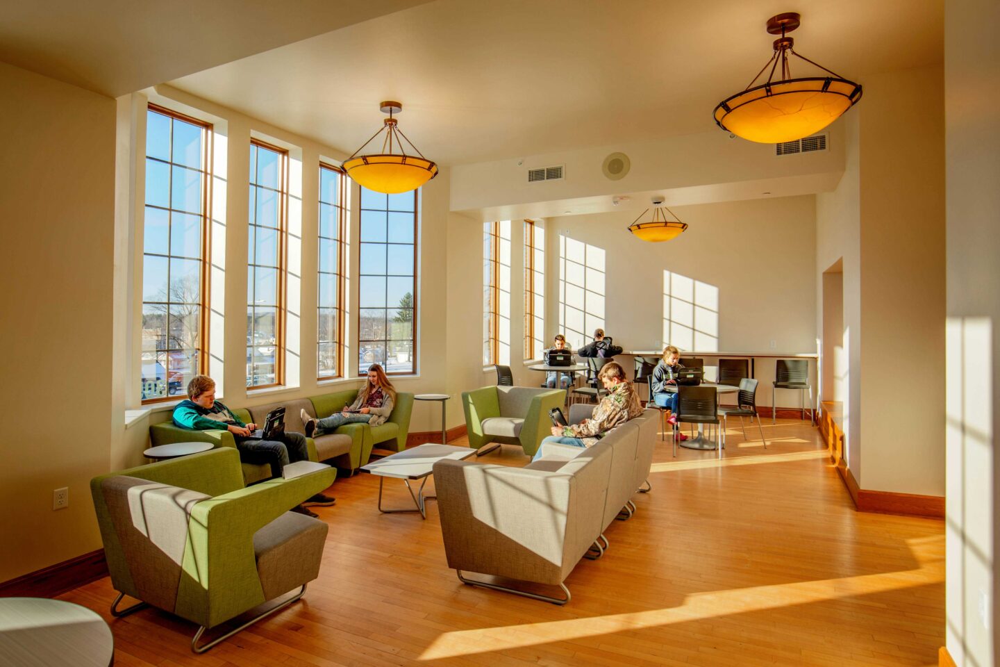 Light pours into an open study space with warm hardwood floors and flexible furniture at Florence Middle + High School