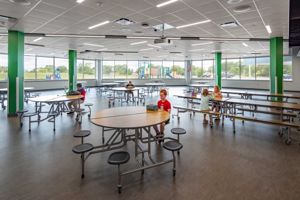 Students use multiple seating options in a cafeteria lined with large windows at Highland View Elementary School in Greendale