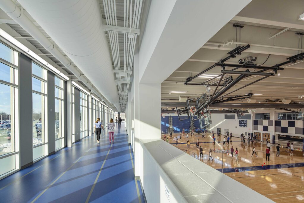 An elevated indoor track overlooks an active basketball court at Hudson High School