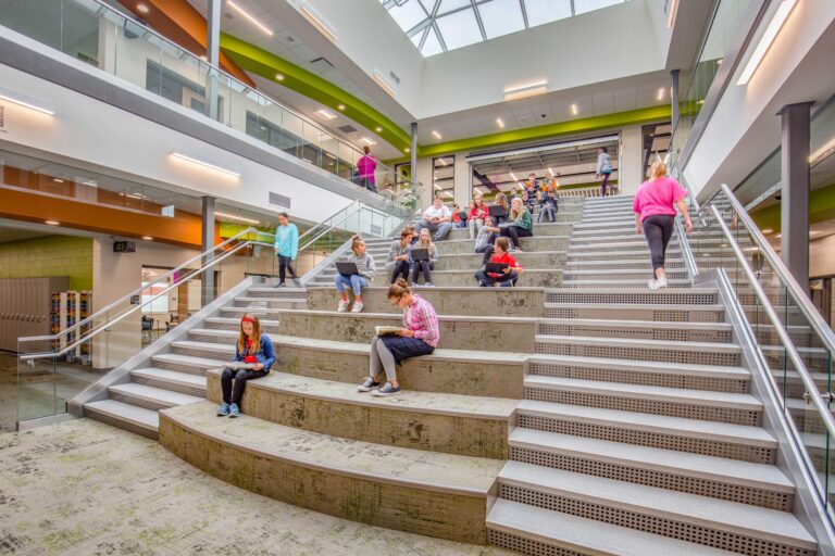 Students gather at the learning stair under a large atrium and skylight