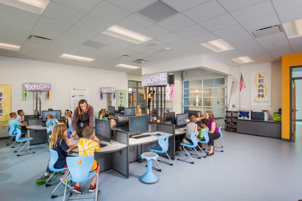 Teachers interacts with students in the school's computer and technology lab, which features an operable garage door for transporting large science projects