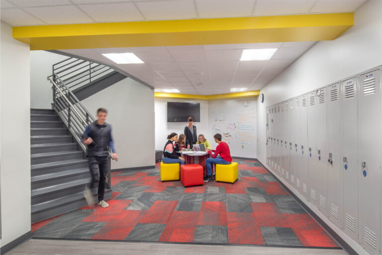 A student descends the stairs to join a small group working in a collaboration area