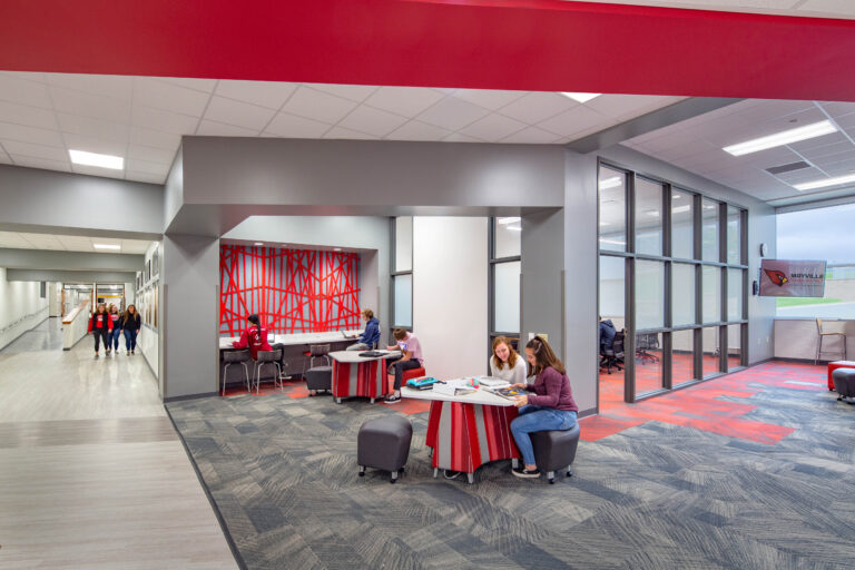 Students collaborate at tables outside of a large, light-filled conference room