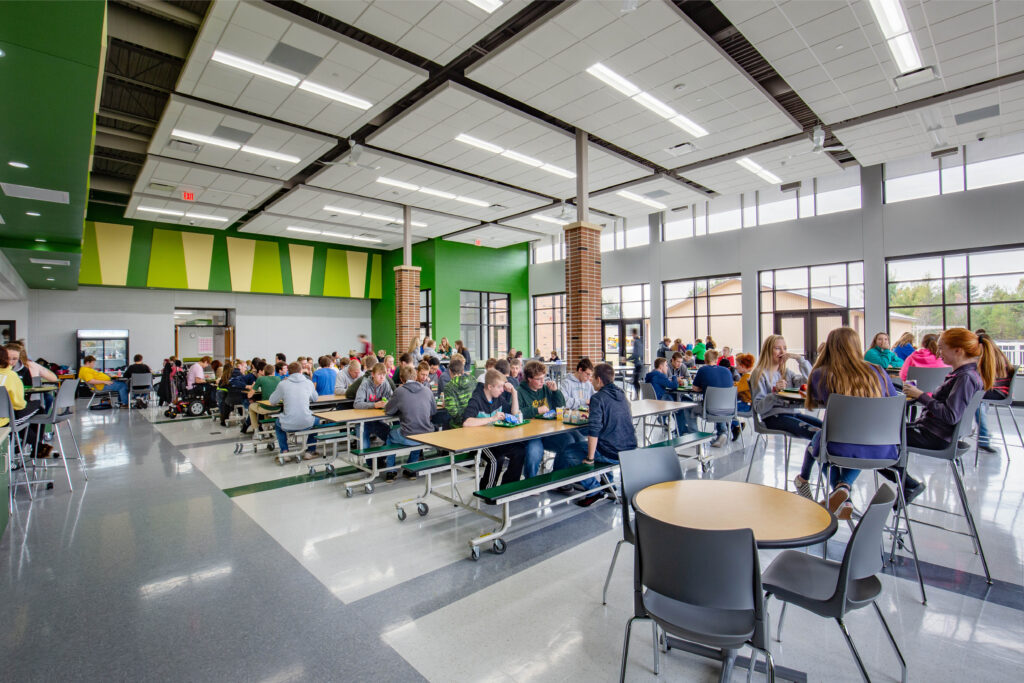Older students gather around tables of varying sizes and shapes in the cafeteria at Melrose-Mindoro High School