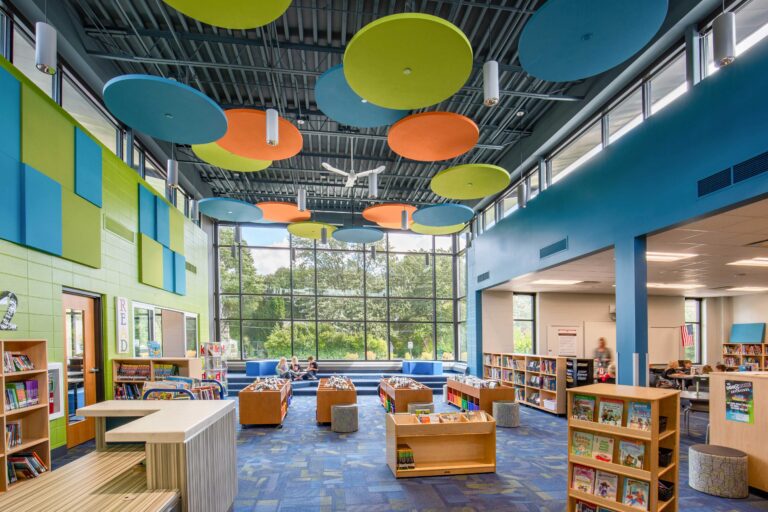 The library features large, floor-to-ceiling windows and color acoustic tiles on the ceiling and walls.